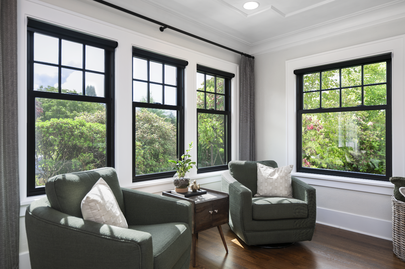 Sunlit room with wood-framed Renewal by Andersen windows overlooking trees